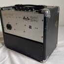Zadní strana černého komba v hliníkovém kufru s rukojetí. Na stříbrném kovovém panelu jsou nápisy "MODEL: 120W-150W", "PBR: NEW", "CE" a "E-10". V ho…
