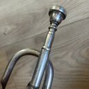 Detailní pohled na hutnou část stříbrného nebo niklovaného dechového nástroje s nasazeným mouturou. Na trubici je vyryt nápis MADE IN CZECHO SLOVAKY.…