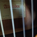 Detail štítku uvnitř akustické kytary. Na bílém štítku s ozdobným rámem je červeným písmem nápis Alhambra a pod ním text Made in Spain 1965. V dolní…
