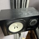 Černý studiový monitor s hranatým korpusem. Na přední straně je bílý membránový reproduktor a menší vysokofrekvenční reproduktor s černou mřížkou. V…
