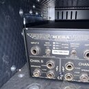 Zadní panel černého kytarového zesilovače značky MESA ENGINEERING. Na panelu jsou nápisy INPUT B, BIAS SWITCH 6L6, GROUND SWITCH LIFT a INPUT A, dále…