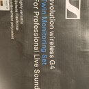 Fotografie zachycuje černou krabici s bílými a modrými nápisy. Je na ní vidět logo značky Sennheiser a texty „evolution wireless G4“, „Twin Monitorin…