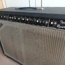 Černý kytarový kombozesilovač s šedou textilní maskou a koženým úchytem. Na předním panelu jsou nápisy Fender, Twin Reverb a PENDER MUSICAL INSTRUMEN…
