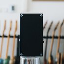 Černý obdélníkový kousek elektroniky v kovovém šasi, zřejmě efekt pedál, zobrazený z horní strany. Povrch je matně černý a v rozích jsou vidět čtyři…