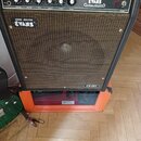 Černý kytarový kombo zesilovač s hnědou textilní mřížkou. Na horním ovládacím panelu jsou nápisy CREATIVE SOUND ®, Evans MUSICAL AMPLIFIER a popisky…