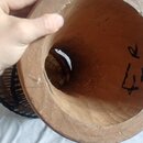 Detailní pohled do vnitřku dřevěného korpusu bubnu s hnědým povrchem. Na vnitřní stěně je černým inkoustem napsán symbol nebo kód "R 4". V dně korpus…