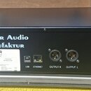 Černý rackový přístroj s nápisem Tegeler Audio Manufaktur na předním panelu. Na zadní straně je bílý štítek s texty Sicherung Fuse 2A träge/slow, Typ…