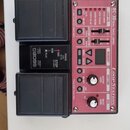 Růžový efekt pedál s nápisy RC-30 DUAL TRACK LOOPER a LoopStation. Zařízení má dvě černé nožní spínače, několik tlačítek a dva otočné ovladače. Na če…