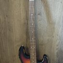 Elektrická basová kytara s korpusem v barevném přechodu od černé přes oranžovou k žluté (sunburst). Na hlavě hmatníku je nápis "Wilkinson ICON Series…