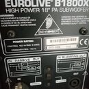 Detailní záběr na zadní štít černého subwooferu. Na štítku je uveden název Eurolive® B1800X HIGH POWER 18" PA SUBWOOFER a značka BEHRINGER. Jsou zde…