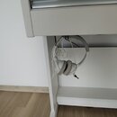 Bílá digitální pianola s přívodním stojanem. Pod klaviaturou visí bílá kabelová sluchátka s kulatými náušníky. Na nástroji ani na sluchátkách nejsou…