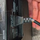 Detailní záběr na zadní panel černého komba s připojeným napájecím kabelem. Na panelu jsou viditelné nápisy EFFECTS, MASTER a MAINS INPUT 100V - 240V…