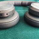 Černá bezdrátová sluchátka s uzavřenými mušlemi a polstrováním z umělé kůže. Na levé mušli jsou vidět ovládací prvky, USB-C port a otvor pro audio ka…