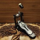 Černý basový pedál s kovovými prvky a stříbrným šlapadlem. Na horní části šlapadla je umístěno oválné logo s nápisem MAPEX. Pedál vykazuje mírné znám…