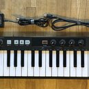 Černý MIDI kontrolér s 37 klávesami. Na levé straně je nápis KEYSTEP 37 controller & sequencer a vpravo logo ARTURIA s přпиisem The sound explorers.…