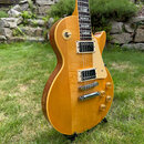 Elektrická kytara typu Les Paul v žluté barvě s viditnou strukturou dřeva. Nástroj má dva humbuckery, čtyři zlaté ovládací knofíky a jeden přepínač t…