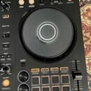 Černý DJ kontrolér s velkým kruhovým jog-wheel uprostřed. Na horní hraně jsou tlačítka s nápisy IN, OUT, 4 BEAT/EXIT a CUE/LOOP CALL, vpravo nápis MA…