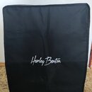 Černý textilní obal na hudební nástroj s obdélníkovým tvarem. V dolní polovině je bílý nápis Harley Benton. Povrch materiálu vykazuje mírné pomačkání…