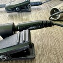 Detailní záběr na černý kabel s konektory a připevněnou svorkou. Na těle konektoru je vyražen nápis MADE IN E56081. Povrch plastů je matně černý s vi…
