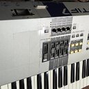 Stříbrný digitální klavír s černými a bílými klávesami. Na levé straně je nápis YAMAHA a na horní hraně modrý pruh s bílým nápisem MOTIF 7. Ovládací…