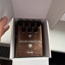 Kytarový efekt pedál v hnědé barvě s kovovým povrchem v textuře broušeného kovu, umístěný v bílém kartonovém krabici. Na horní části jsou ovládací kn…