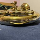 Detailní pohled na mosazný dechový nástroj zlaté barvy. Povrch je výrazně opotřebovaný, s viditelnými škrábanci a odřeninami laku. Na fotce nejsou žá…