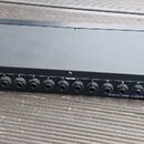 Černý obdélníkový elektronický přístroj s řadou konektorů na předním panelu. Na panelu jsou nápisy POWER 9V AC, FOOTSWITCH, MIDI OUT/THRU, MIDI IN, T…