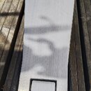 Kovový pedál v stříbrné barvě s matným povrchem. Ve spodní části je vyryté logo Roland. Předmět leží na dřevěném podkladu.