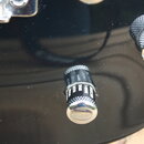 Detailní záběr na černý lakovaný povrch elektrokitary s dvěma ovládacími knoflíky. Knoflíky mají černý vrstvený povrch a chromované konce; na jednom…