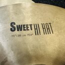 Detailní pohled na mosazný činel s viditelným broušením povrchu. Na čineli je černý nápis SWEET HI HAT a pod ním text 15"/38 cm TOP. Povrch vykazuje…