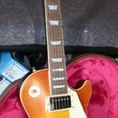Elektrická kytara typu Les Paul s barevným přechodem od žluté k červené (sunburst) a krčkem z tmavého dřeva s bílými trámkovými vložkami. Na hlavě je…