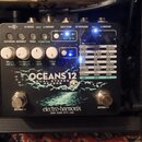 Šedý efekt pedál s nápisy OCEANS 12, DUAL STEREO REVERB a značkou electro-harmonix NEW YORK CITY, USA. Zařízení má několik bílých otočných ovladačů a…