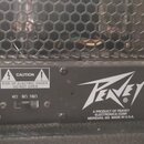 Detail zadní strany kytarového komba s černým povrchem a kovovou mřížkou. Je zde vidět logo Peavey s nápisem A PRODUCT OF PEAVEY ELECTRONICS CORP MER…
