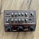 Šedý efektový pedál s nápisy BOSS a Acoustic Preamp AD-10. Zařízení obsahuje řadu otočných potenciometrů, tlačítek a konektorů na horní i zadní stran…