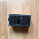 Fotografie zachycuje spodní stranu černého elektronického zařízení s šedým rámem. Na spodní části je přilepený široký černý textilní suchý spoj. Mezi…