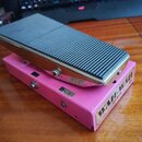 Růžový wah-wah pedál s černou gumovou texturovanou plochou šlapadla. Na boku je viditelný nápis „WAH-WAH switch“ a dvě černé štítky s označením „8 V…