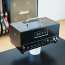Černý kytarový zesilovač s nápisem REVV na předním panelu a rukojetí z nerezové oceli na horní straně. Na spodním ovládacím panelu jsou nápisy D20, I…
