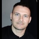 Na fotografii není zobrazen žádný hudební nástroj ani příslušenství. Je zde vidět portrét muže v černém polo tričku.