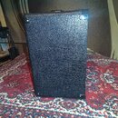 Fotografie zachycuje zadní stranu černého kytarového komba s povrchem z texturovaného vinylu. Rohy jsou chráněny plastovými nebo kovovými černými zpe…