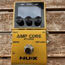 Zlatý efekt pedál s nápisy AMP CORE STUDIO a NUX. Horní část obsahuje displej, tři černé ovládací knoflíky a konektory USB, DC 9V a MIDI. Na spodní č…