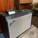 Černý kytarový kombo zesilovač s bílou textilní mřížkou. Na horním ovládacím panelu je nápis Fender Frontman 212R a řada ovladačů. Na přední mřížce j…