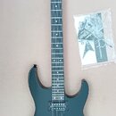 Černá elektrická kytara s typickým špičatým hřátem, na kterém je bílý nápis Jackson. Nástroj má dva humbuckery, strunovou kotvu a černý hardware. Ved…