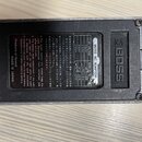 Zadní strana černého napájecího adaptéru s logem BOSS. Na štítku je uveden nápis BOSS AC ADAPTOR a tabulka s napětím AC VOLTAGE (100V, 117V, 220V) a…