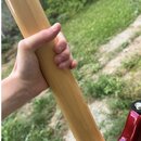 Fotografie zachycuje detail krku elektrického nástroje s červeným lakovaným trupem. Krk je vyroben ze světlého dřeva s hladkým povrchem. Nástroj drží…