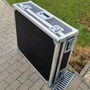 Černý transportní flightcase s hliníkovými hranami a kovovými rohy. Na horní straně jsou dvě zapínací zámky a jedna přenosná rukojeť. Boční strana ob…