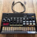Černý sekvenční syntezátor Korg Volca Beats s bílými nápisy a ovládacími prvky. Zařízení obsahuje několik otočných potenciometrů, bílá tlačítka a v d…