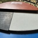 Fotografie zobrazuje tři gumové cvičné pady pro bubeníky v polokruhovém tvaru. Horní červený pad nese bílý nápis drumeo P4 Practice Pad. Pod ním jsou…