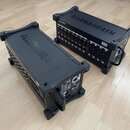 Dvě černé rackové jednotky značky ALLEN&HEATH umístěné na dřevěné podlaze. Jednotka vpravo nese nápis DX168 MixerExpand. Obě zařízení mají na horní s…