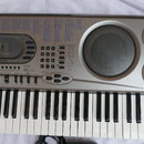 Stříbrný digitální klavír značky CASIO s nápisem MUSICAL INFORMATION SYSTEM. Nástroj má v pravé části tři kulaté reproduktory a v horní části rozsáhl…
