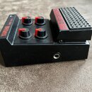 Černý kytarový efekt s integrovaným pedálem, který má na horní části nápisy YAMAHA a MBD-20M. Zařízení obsahuje čtyři červené ovládací knoflíky s pop…